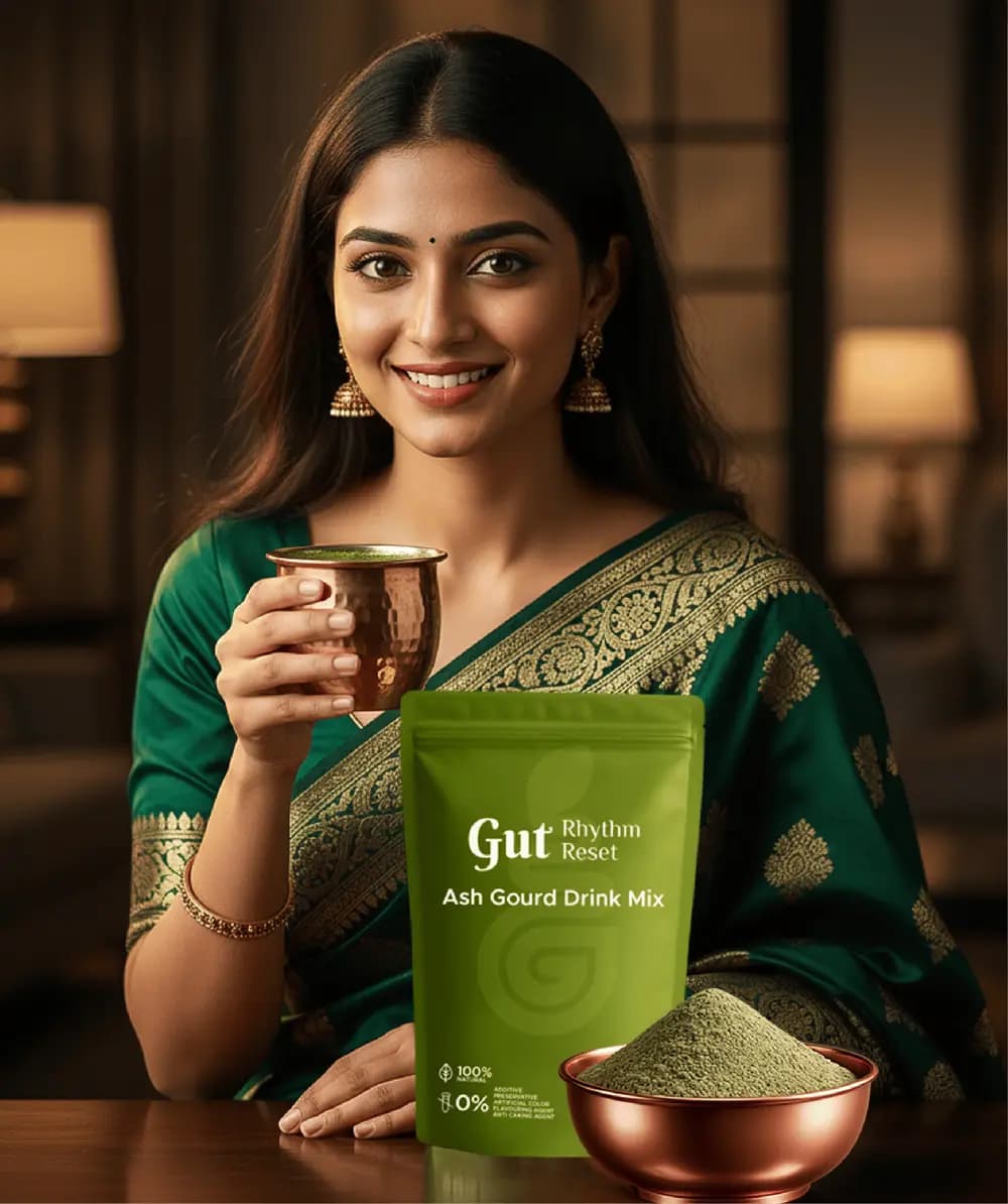 A woman in a green saree with a copper tumbler of Ash Gourd drink, the pouch and a bowl of powder beside her