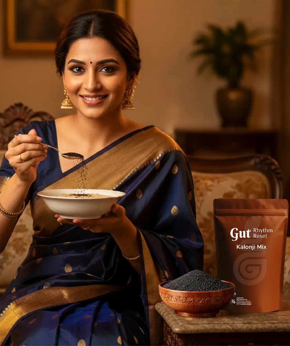 A woman in a navy saree with a bowl of Kalonji Mix beside the pouch